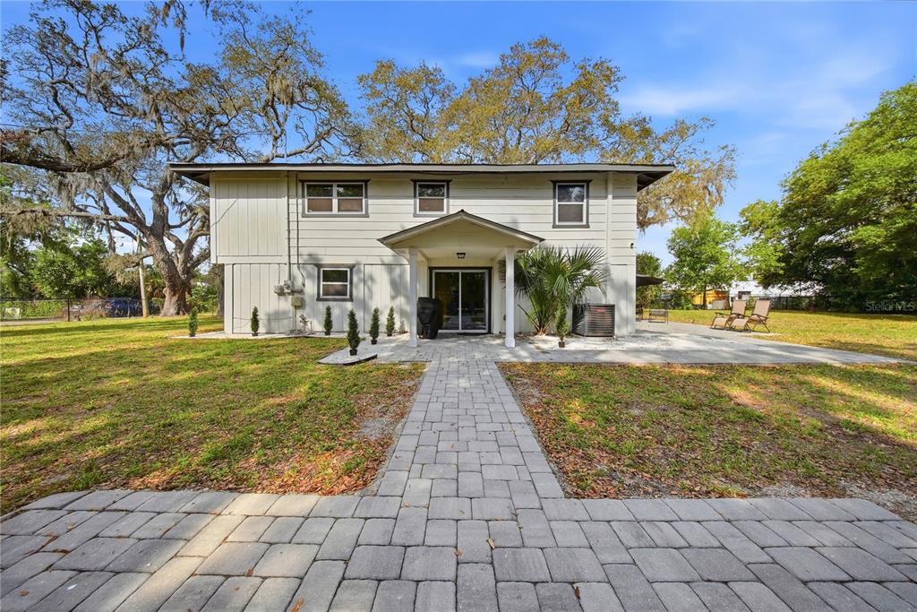 A two-story house with light-colored siding features a paved walkway leading to a covered entrance — 6902 E 29TH AVENUE, TAMPA, FL