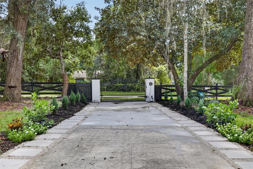 A concrete driveway leads to a gated entrance flanked by white pillars and black fencing — 300 SCOTT ROAD, GENEVA, FL