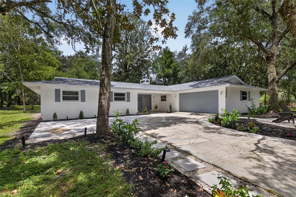 A white, single-story ranch-style house with a gray garage door and a circular concrete driveway — 300 SCOTT ROAD, GENEVA, FL