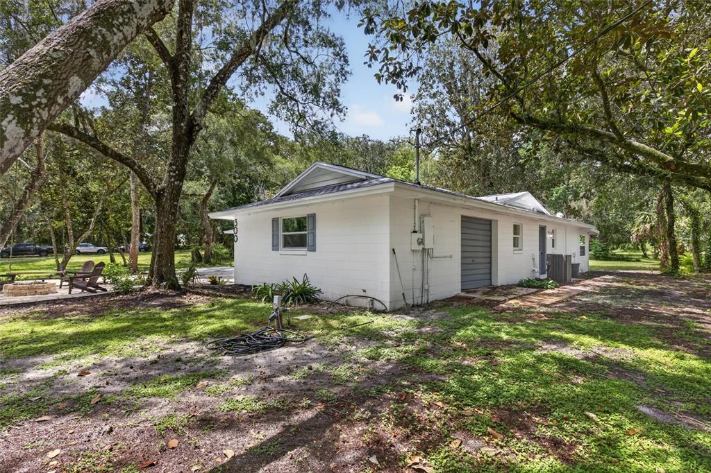 A white concrete block house with a gray garage door sits on a grassy, wooded lot — 300 SCOTT ROAD, GENEVA, FL