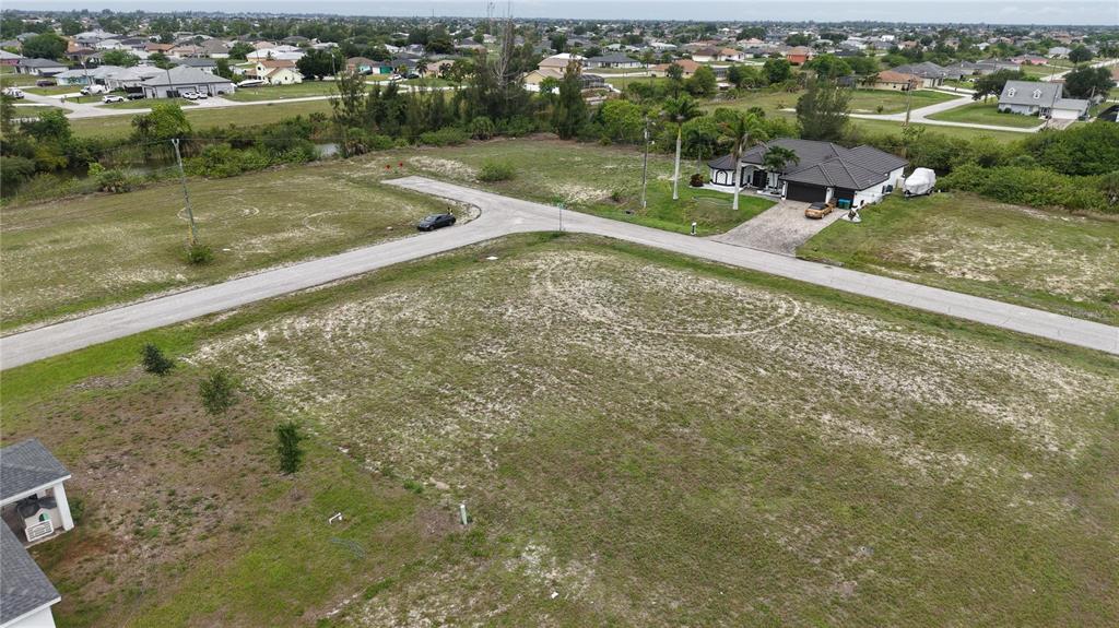 An aerial view shows a vacant corner lot in a residential neighborhood with paved roads — 2009 NW 2ND AVENUE, CAPE CORAL, FL