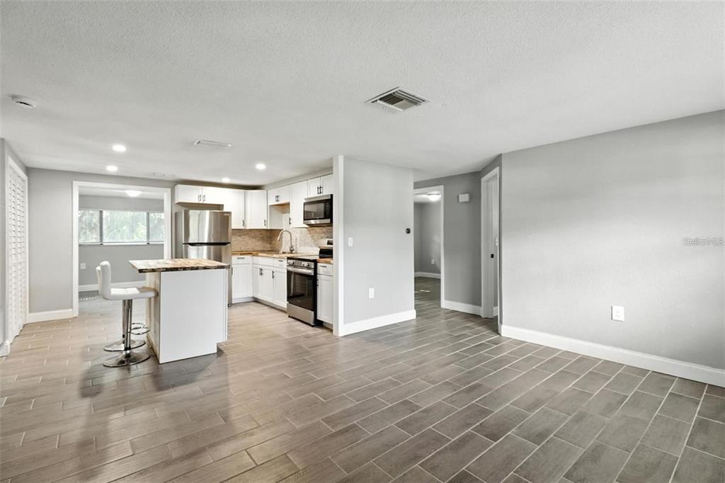 A kitchen with white cabinets, stainless steel appliances, and a small island with seating — 8035 GULF WAY, HUDSON, FL