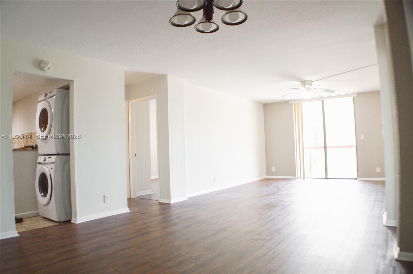 A living room with wood-look flooring, a ceiling fan, and a stacked washer and dryer — 733 SE 1st Way # 206, Deerfield Beach FL 33441, DEERFIELD BEACH, FL