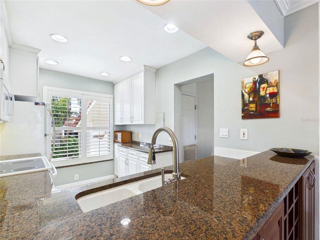 A kitchen features white cabinetry, granite countertops, a double sink, and plantation shutters — 6335 PALMA DEL MAR BOULEVARD S UNIT 223, ST PETERSBURG, FL