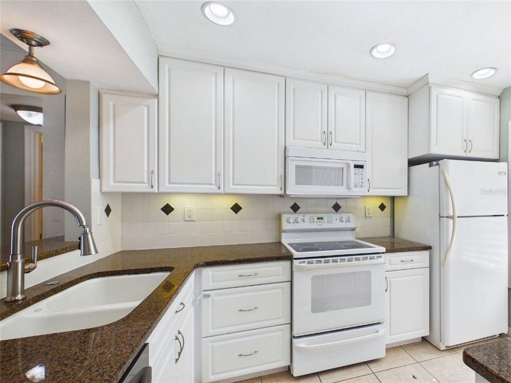A kitchen with white cabinets, granite countertops, a white stove, and a white refrigerator — 6335 PALMA DEL MAR BOULEVARD S UNIT 223, ST PETERSBURG, FL