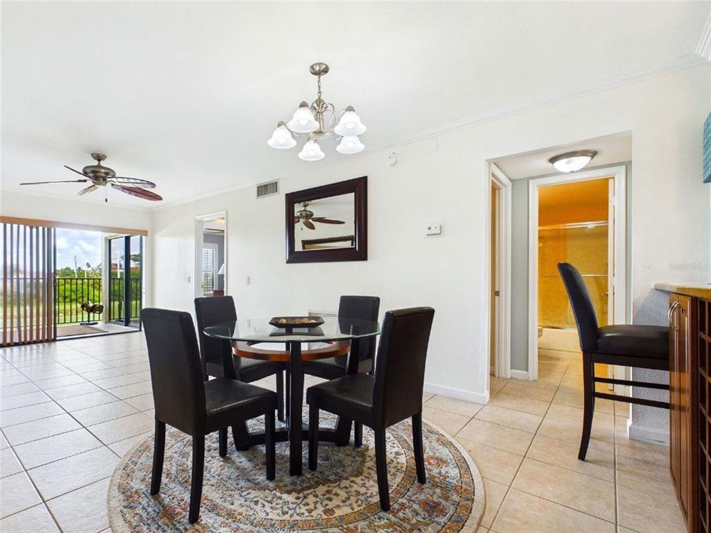 A dining area with a glass table, four chairs, tile flooring, and a sliding glass door — 6335 PALMA DEL MAR BOULEVARD S UNIT 223, ST PETERSBURG, FL
