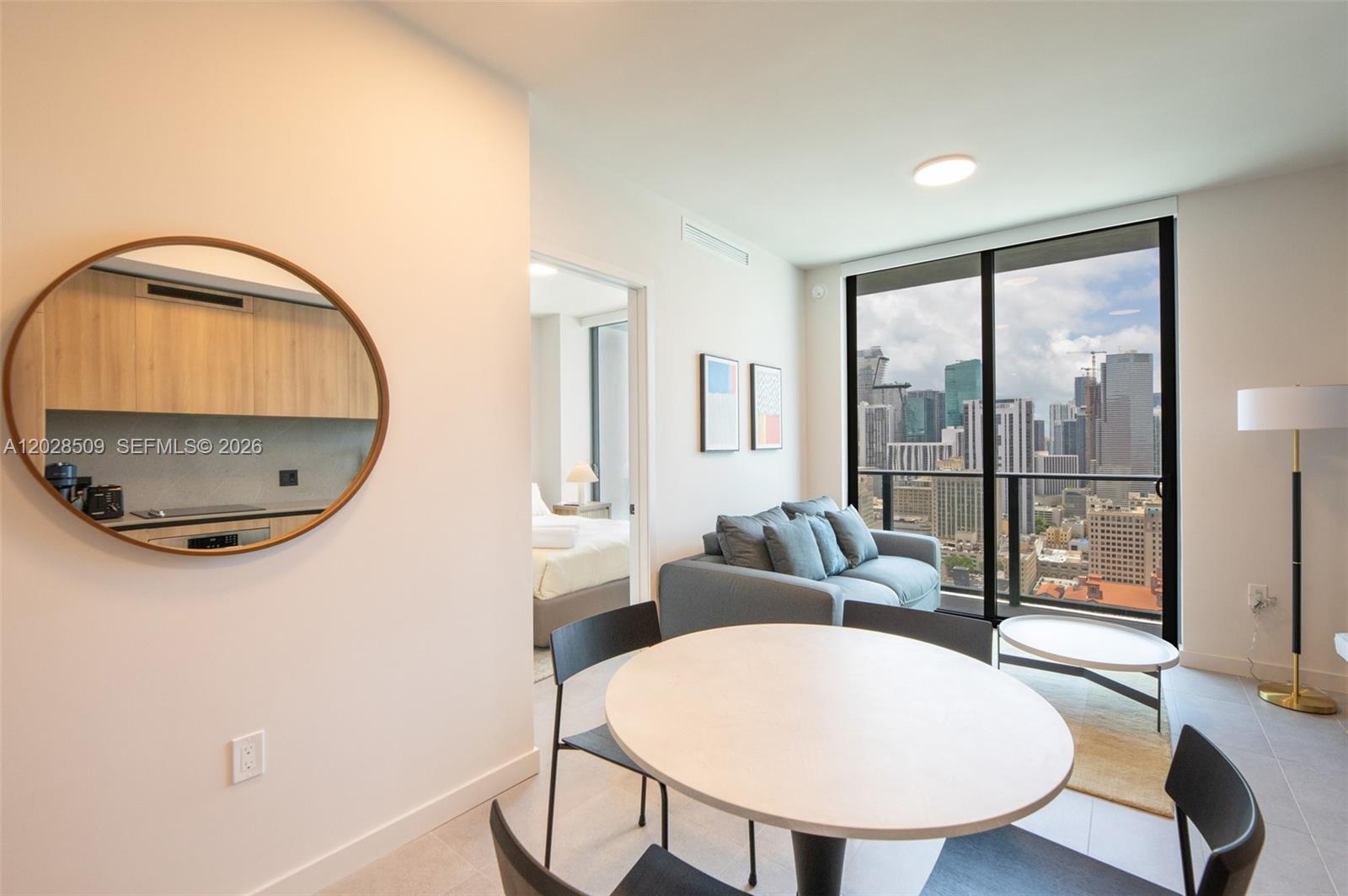 A modern apartment living area features a dining table, sofa, and city skyline views — 121 NE 5th St # 3102, Miami FL 33132, MIAMI, FL