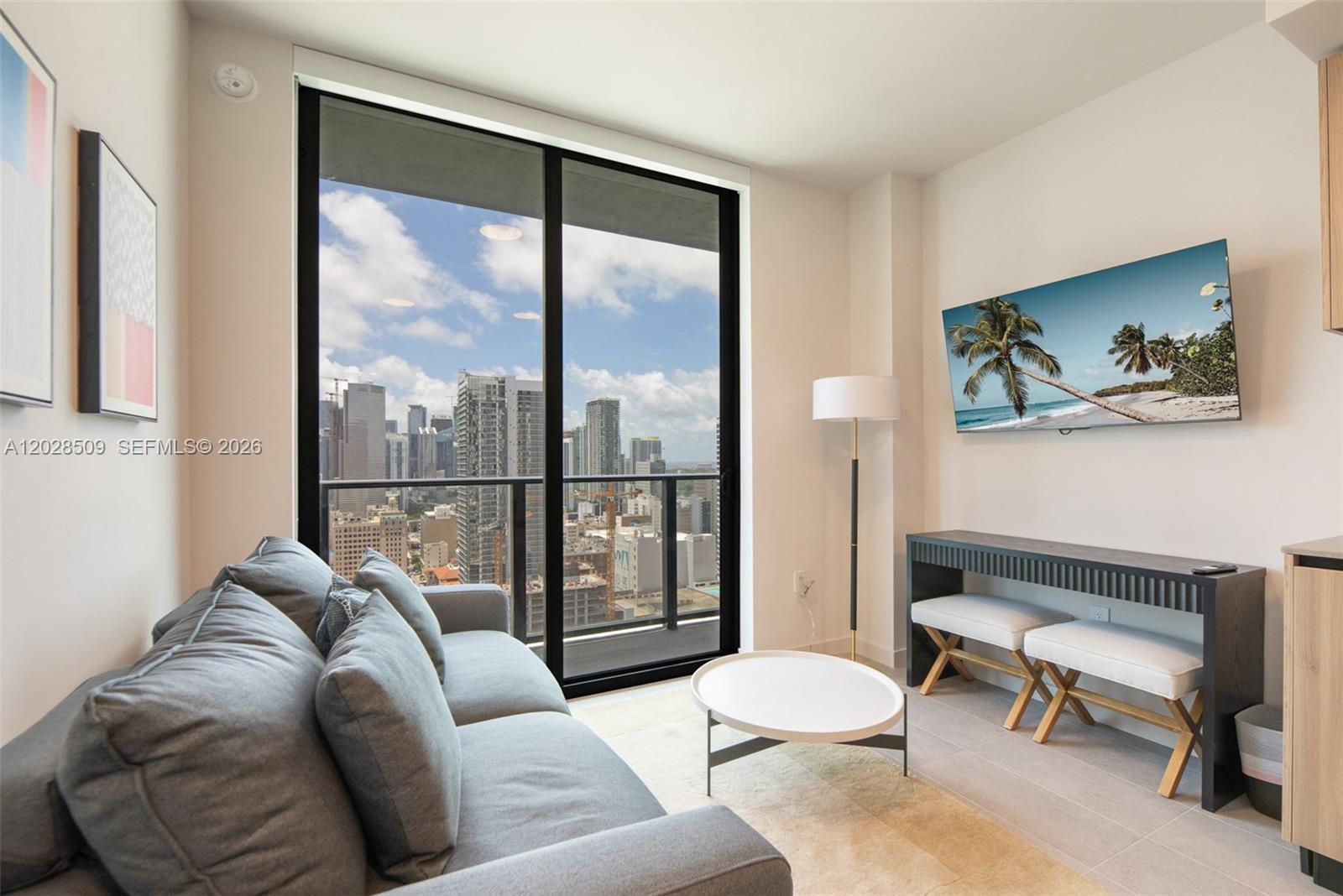 A living room features a gray sofa, a white coffee table, and a city view — 121 NE 5th St # 3102, Miami FL 33132, MIAMI, FL