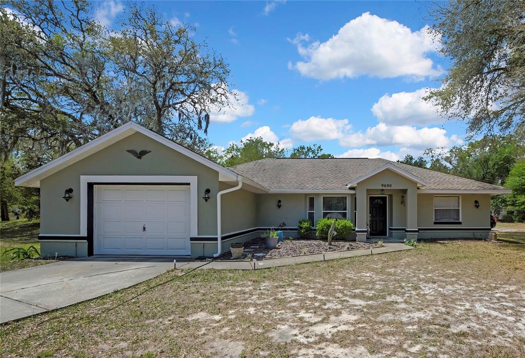 A single-story house with a green exterior, a white garage door, and a covered entryway — 9690 N ALDER AVENUE, CRYSTAL RIVER, FL