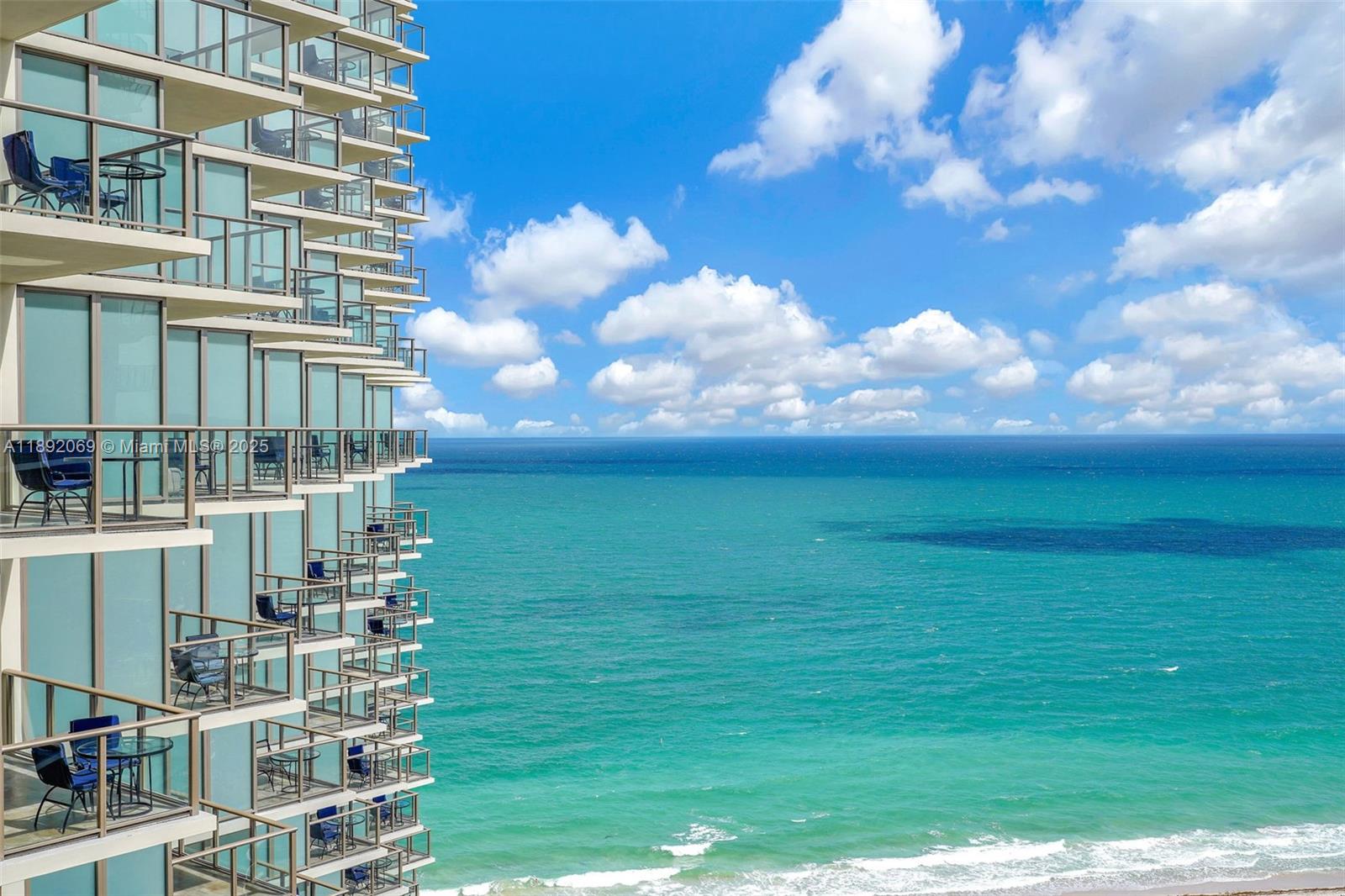 A high-rise building with multiple balconies overlooks the ocean under a blue sky — 9701 Collins Ave # 2103S, Bal Harbour FL 33154, BAL HARBOUR, FL
