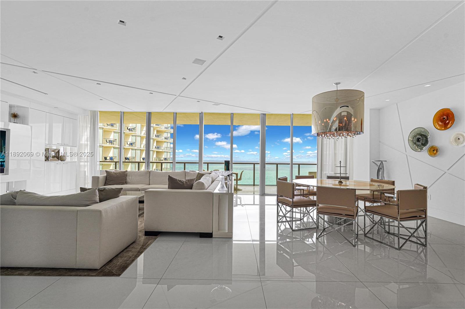 A modern living and dining area features white tile floors, neutral furniture, and ocean views — 9701 Collins Ave # 2103S, Bal Harbour FL 33154, BAL HARBOUR, FL
