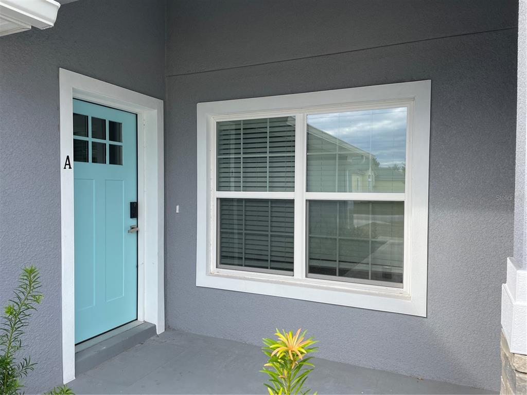A light blue front door with a window sits next to a large white-framed window — 110 LYNBROOK DRIVE UNIT A, PALM COAST, FL