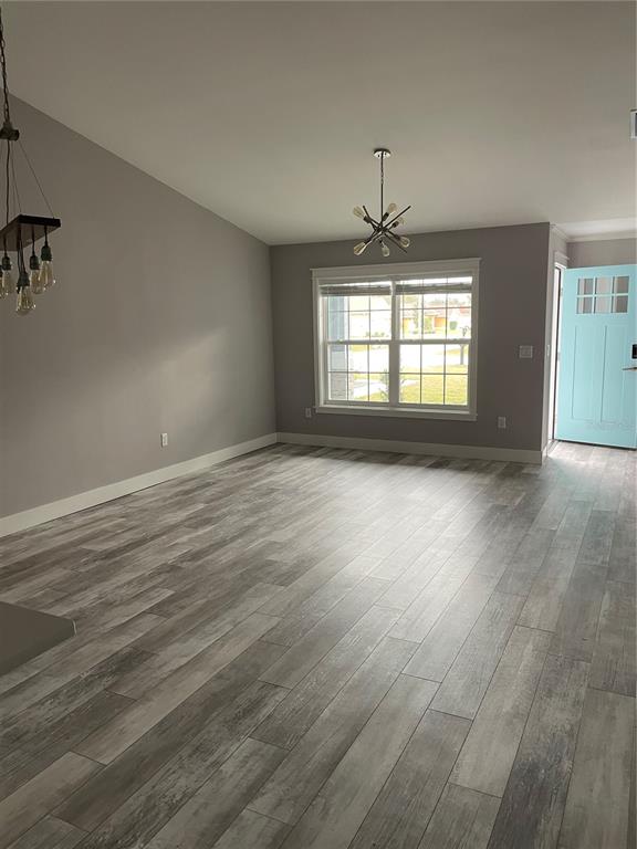 A living room with gray walls, wood-look plank flooring, a modern chandelier, and a blue door — 110 LYNBROOK DRIVE UNIT A, PALM COAST, FL