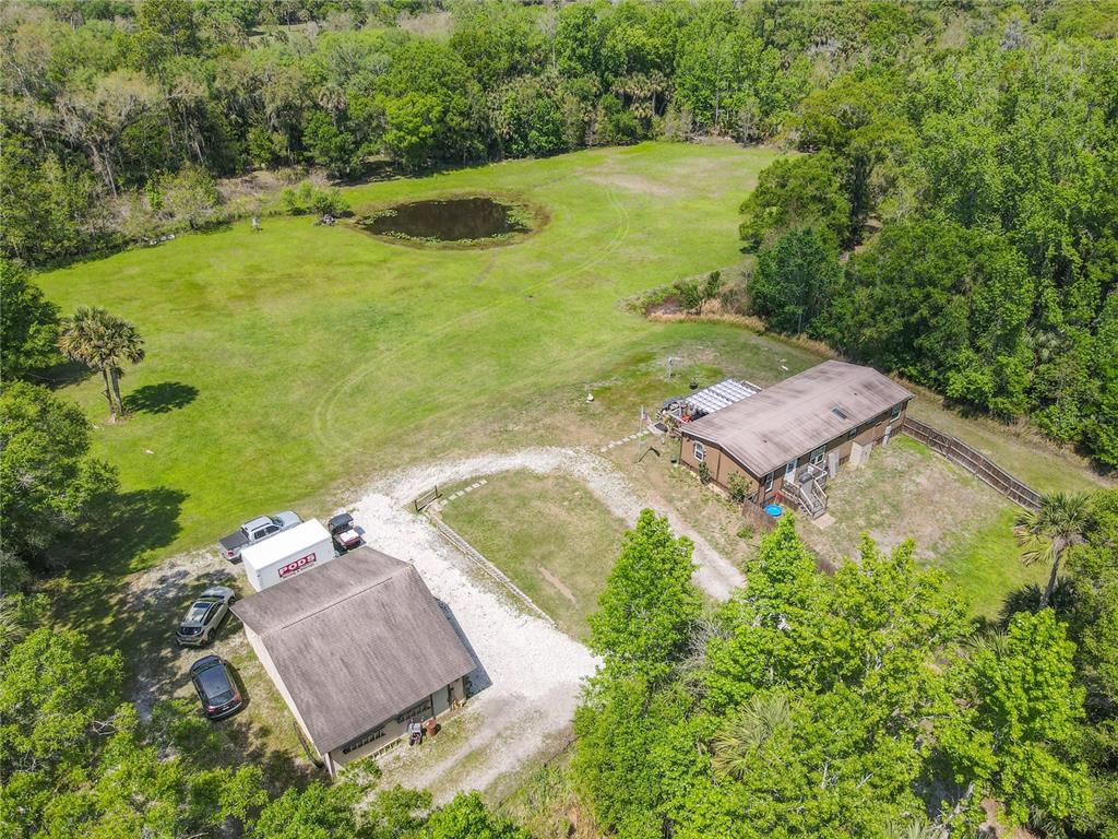 An aerial view shows a house and detached garage on a large, grassy rural lot — 1501 ASHBY CREEK ROAD, OSTEEN, FL