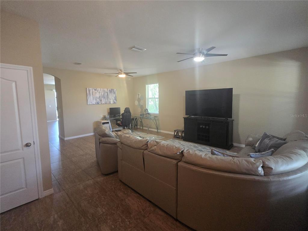 A living room features a large sectional sofa, a television on a stand, and a desk — 8451 KARPEAL DRIVE, SARASOTA, FL