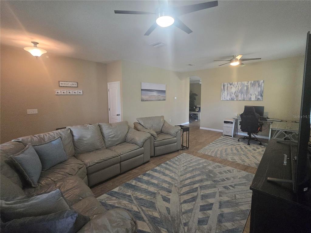 A living room features a large sectional sofa, a desk area, and two ceiling fans — 8451 KARPEAL DRIVE, SARASOTA, FL