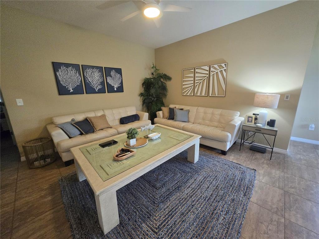 A living room features two white sofas, a glass-top coffee table, and coastal-themed wall art — 8451 KARPEAL DRIVE, SARASOTA, FL
