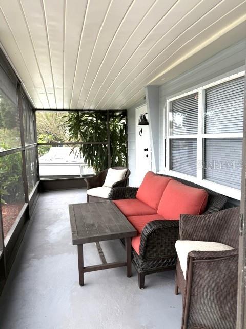 A screened-in porch features wicker furniture, a wooden coffee table, and windows with blinds — 5200 76TH STREET N, ST PETERSBURG, FL