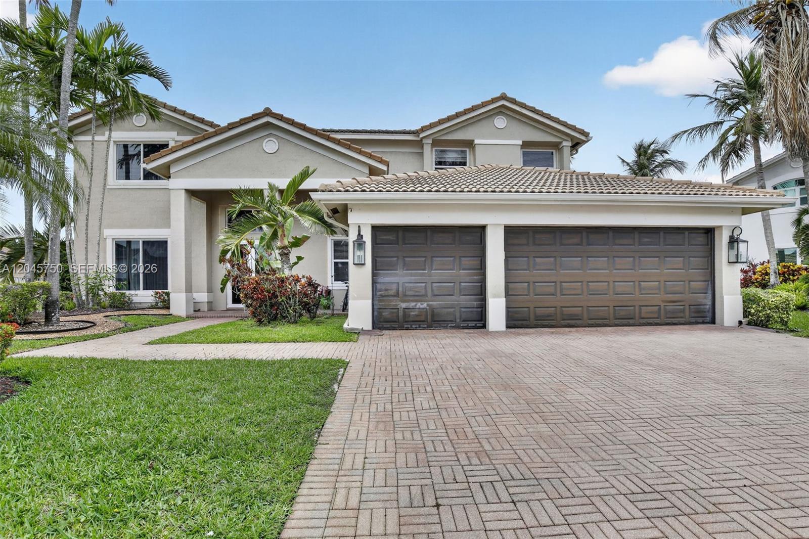 A two-story house features a paved driveway, a two-car garage, and palm trees — 981 Waterside Cir, Weston FL 33327, WESTON, FL