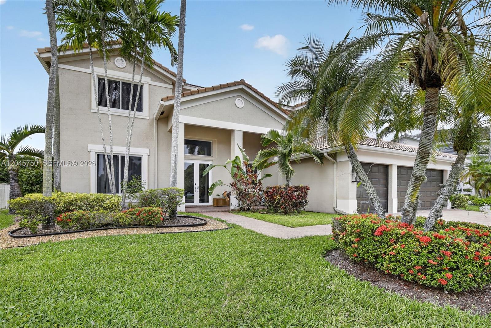 A two-story suburban house with a beige exterior, a tiled roof, and palm trees — 981 Waterside Cir, Weston FL 33327, WESTON, FL