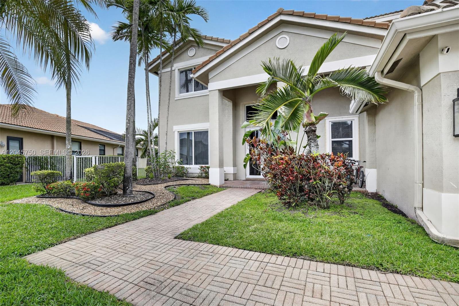 A two-story house with a paved walkway, palm trees, and landscaping in the front yard — 981 Waterside Cir, Weston FL 33327, WESTON, FL