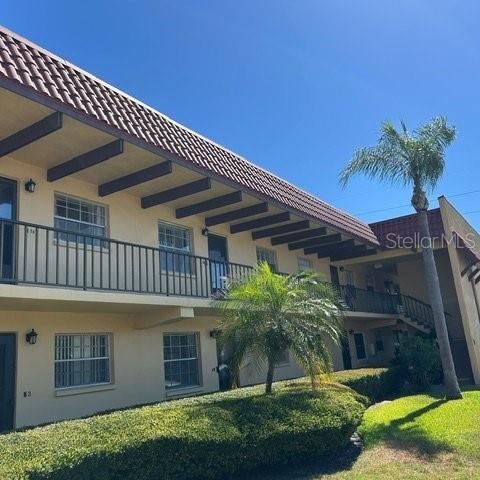 A two-story apartment building features a brown tiled roof, exterior walkways, and a palm tree — 1845 S HIGHLAND AVENUE UNIT 15, LARGO, FL