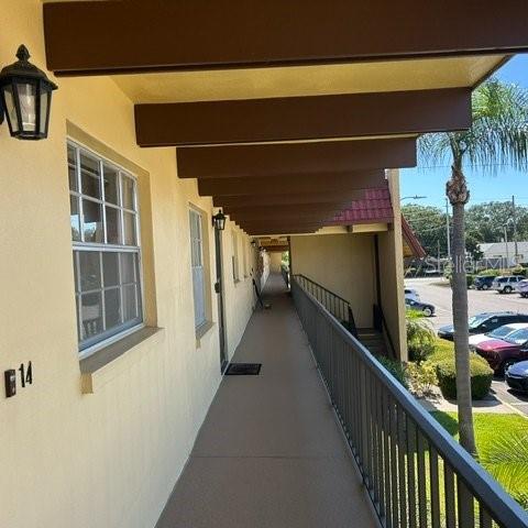 An exterior walkway with a covered ceiling and metal railing overlooks a parking lot — 1845 S HIGHLAND AVENUE UNIT 15, LARGO, FL