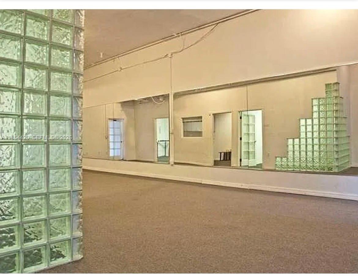 A room with carpeted flooring, mirrored walls, and decorative glass block partitions — 710 W 51st St, Miami Beach FL 33140, MIAMI BEACH, FL