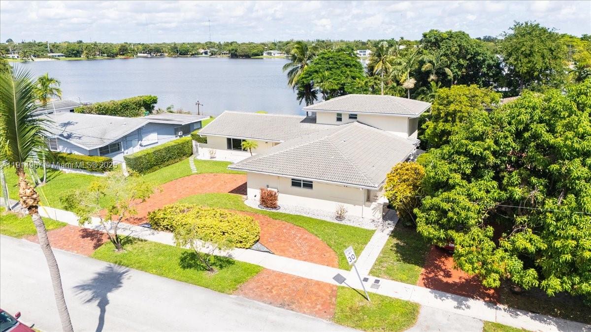 An aerial view shows a single-story house with a tiled roof near a lake — 1961 NE 188th St, Miami FL 33179, MIAMI, FL
