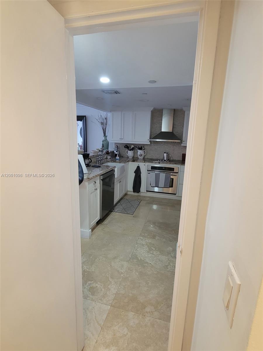 A view through a doorway shows a kitchen with white cabinets and stone flooring — 2625 Collins Ave # 1601, Miami Beach FL 33140, MIAMI BEACH, FL