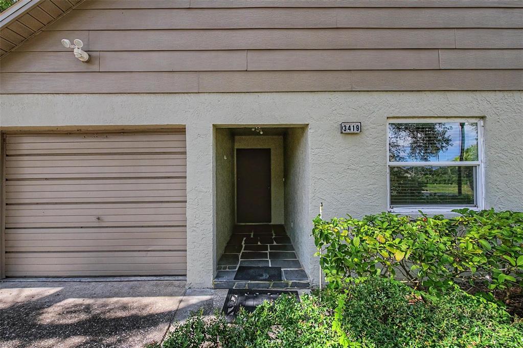 The exterior of a home features a garage, a recessed entryway, and a single window — 3419 ANNETTE COURT, CLEARWATER, FL