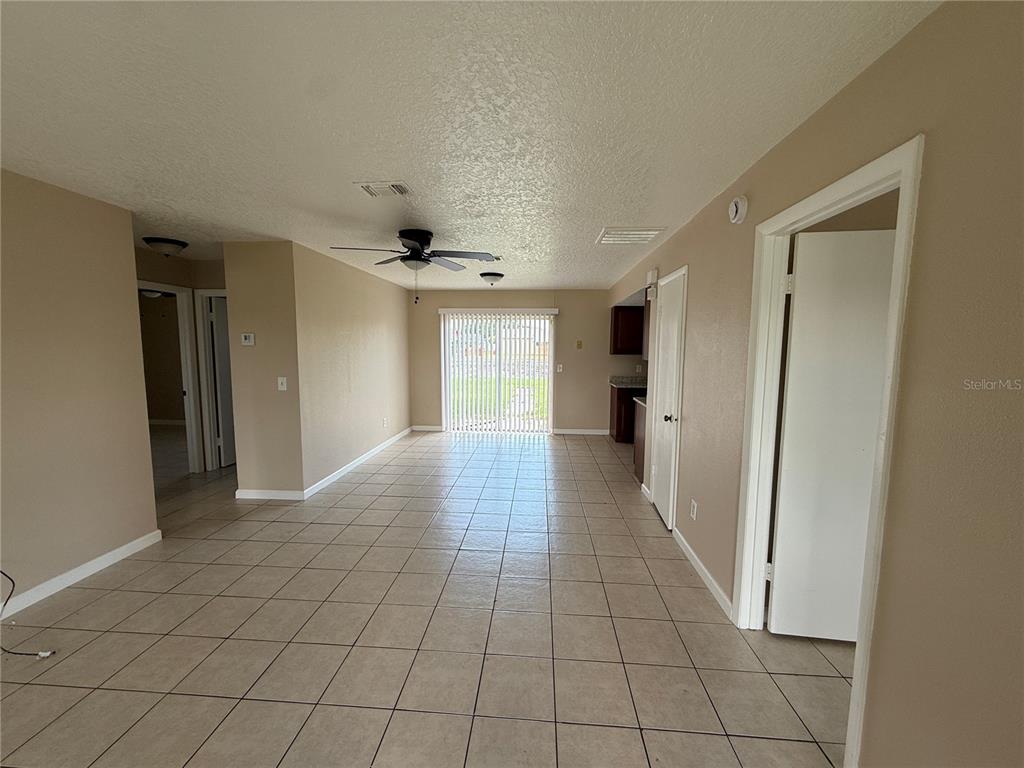 An open-concept living and dining area features tile flooring, a ceiling fan, and sliding doors — 133 ALDERWOOD DRIVE, KISSIMMEE, FL