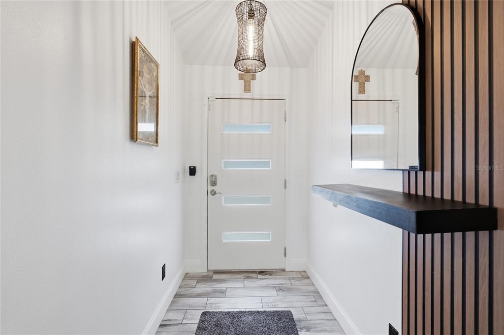 A modern entryway features a white door with glass panels, a wood-slat wall, and mirror — 10924 SW 48TH TERRACE, OCALA, FL