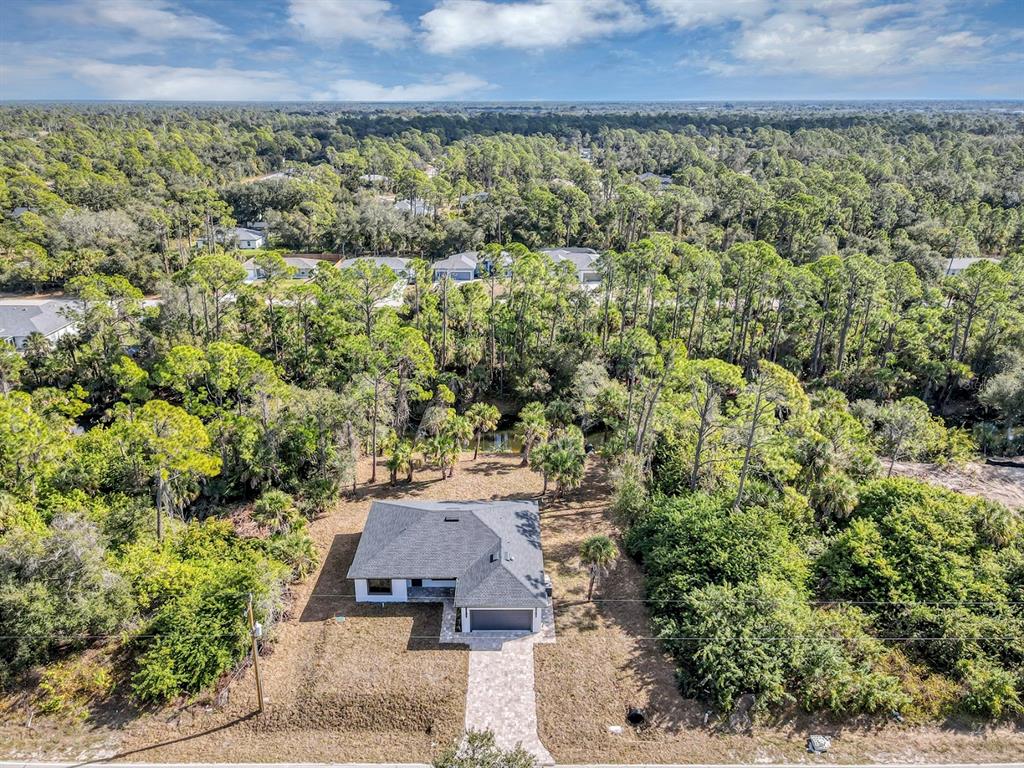 An aerial view shows a single-story house with a gray roof surrounded by dense woods — 72 SHORELAND STREET, PORT CHARLOTTE, FL