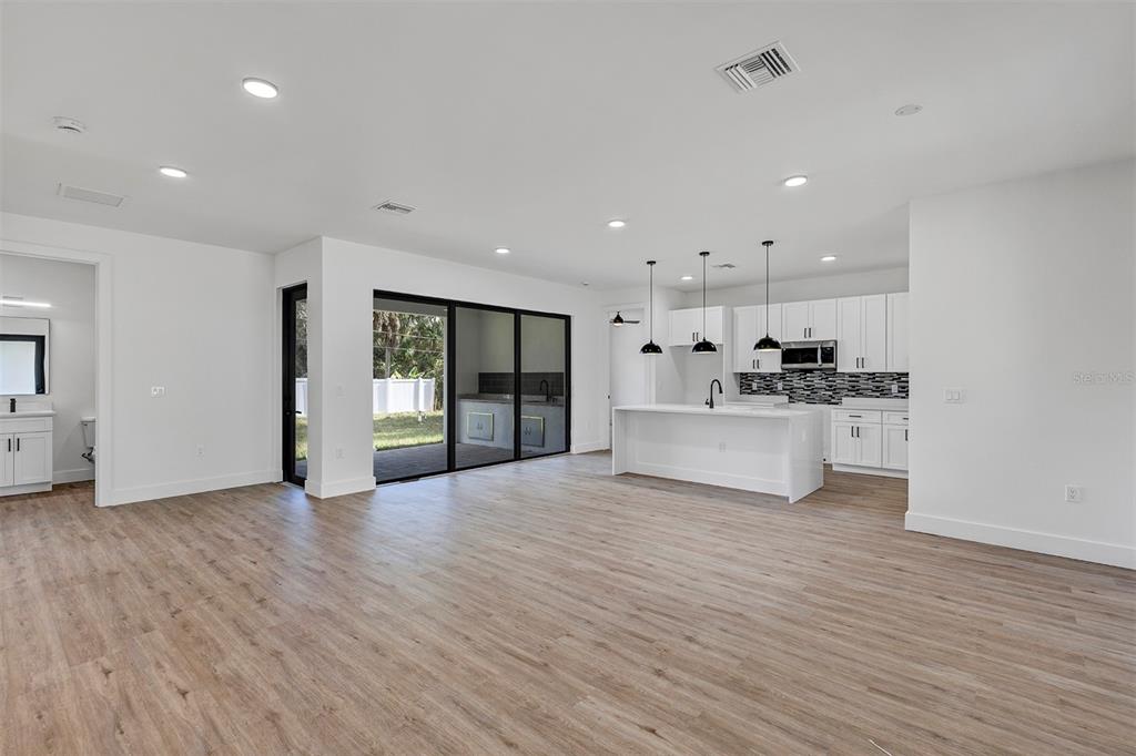 An open-concept kitchen and living area features white cabinetry, a central island, and wood-look flooring — 72 SHORELAND STREET, PORT CHARLOTTE, FL