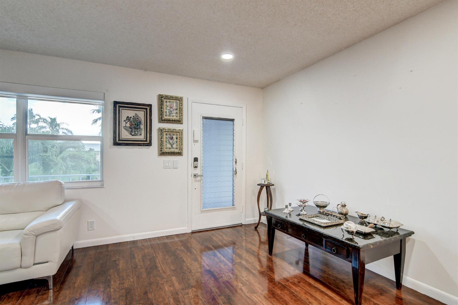 A living room features a white sofa, a dark wood console table, and a front door — 42 Burgundy A # A, Delray Beach FL 33484, DELRAY BEACH, FL