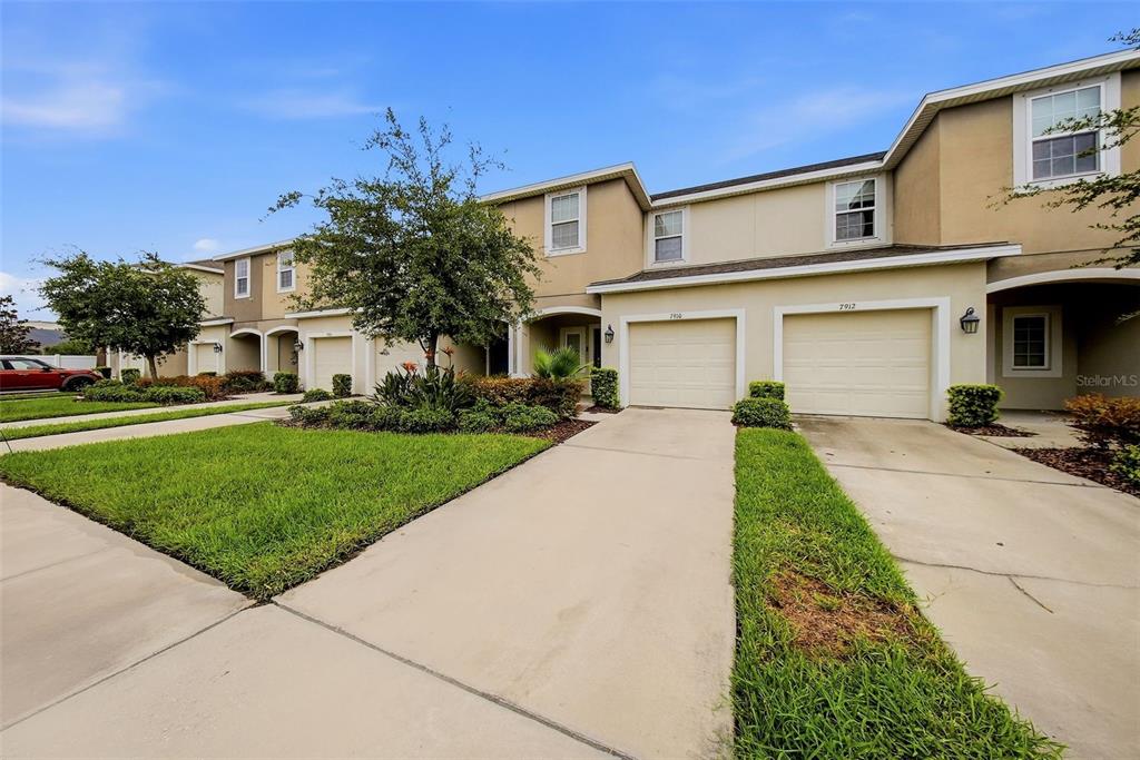 A row of two-story townhomes with beige stucco exteriors, attached garages, and concrete driveways — 7910 EVERGREEN CREEK COURT, RIVERVIEW, FL