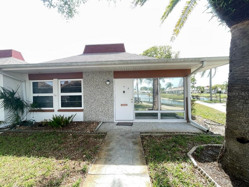 A single-story home with a stone facade, white door, and a stone walkway — 4326 TAHITIAN GARDENS CIRCLE UNIT 14E, HOLIDAY, FL
