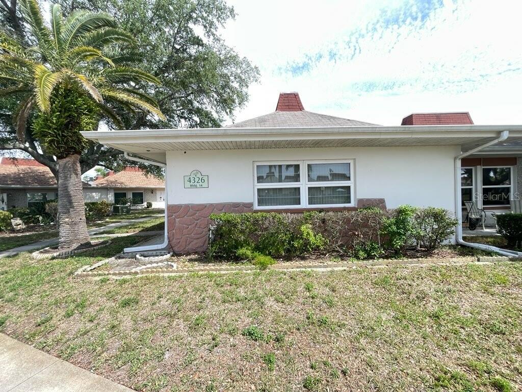 A single-story building with white stucco walls, a stone facade, and a hip roof — 4326 TAHITIAN GARDENS CIRCLE UNIT 14E, HOLIDAY, FL
