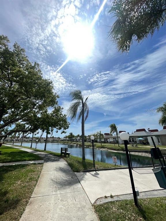 A paved walkway leads past a small pond and palm trees toward residential buildings — 4326 TAHITIAN GARDENS CIRCLE UNIT 14E, HOLIDAY, FL