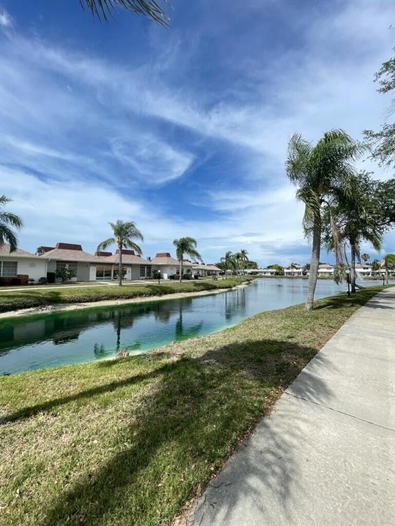 A concrete walkway runs alongside a canal lined with palm trees and residential buildings — 4326 TAHITIAN GARDENS CIRCLE UNIT 14E, HOLIDAY, FL