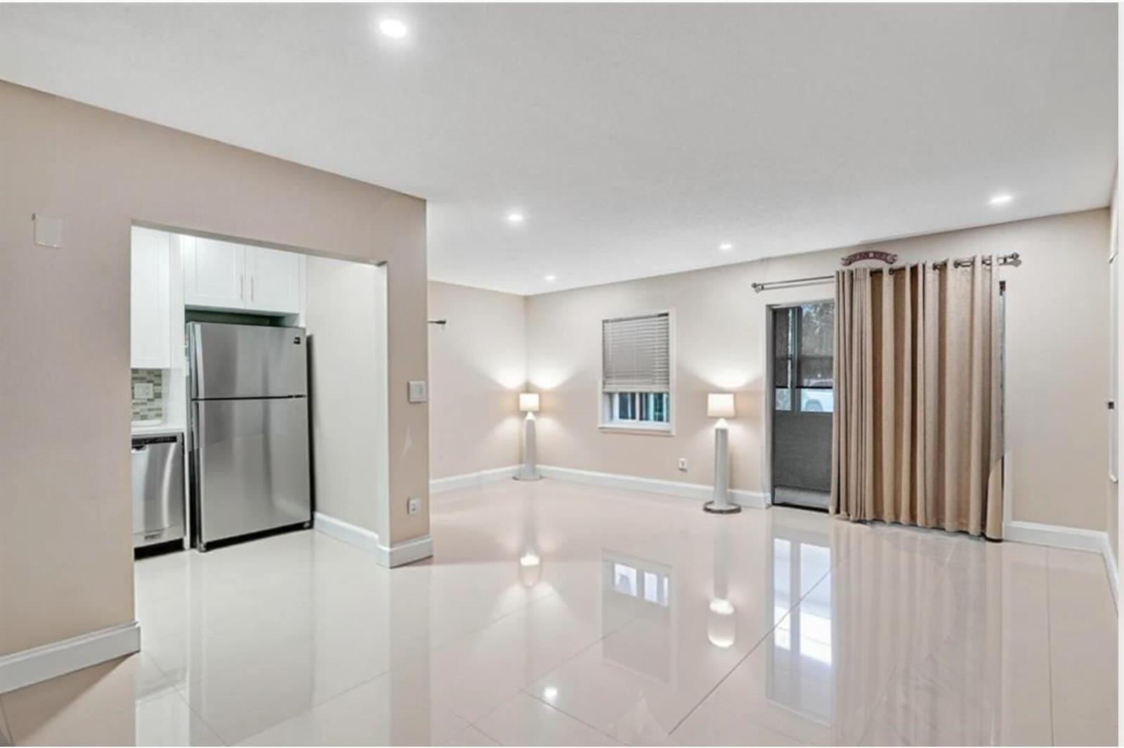 An open-concept living area with glossy tile floors, recessed lighting, and an adjacent kitchen — 4980 E Sabal Palm Boulevard E # 124, Tamarac FL 33319, TAMARAC, FL