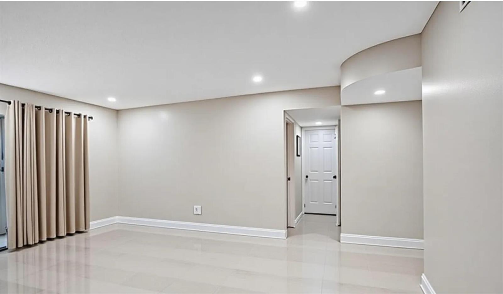 An empty room with beige walls, light tile flooring, recessed lighting, and beige curtains — 4980 E Sabal Palm Boulevard E # 124, Tamarac FL 33319, TAMARAC, FL