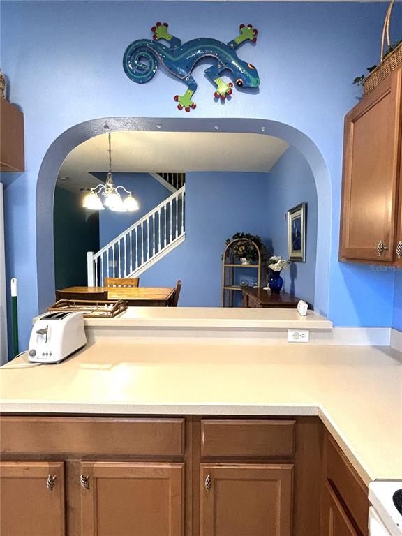 A kitchen counter overlooks a dining area with a staircase through an arched wall opening — 3825 45TH TERRACE W UNIT 104, BRADENTON, FL