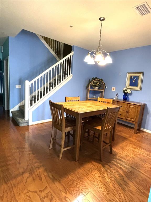 A dining area features a wooden table, four chairs, a chandelier, and a staircase — 3825 45TH TERRACE W UNIT 104, BRADENTON, FL