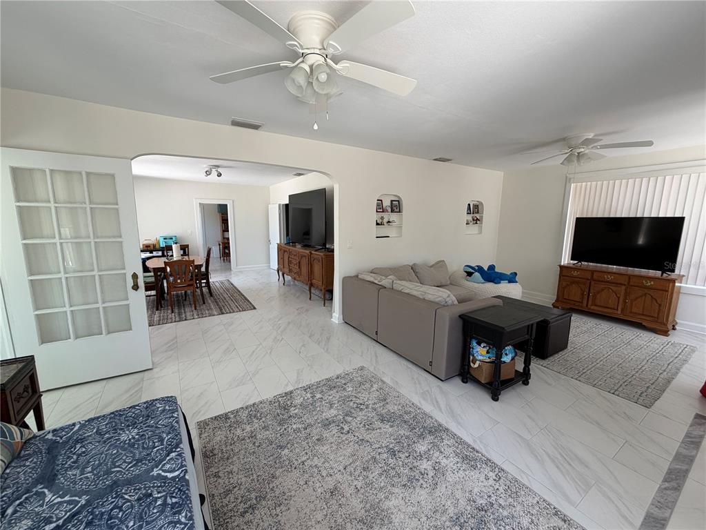 A living room with white tile floors, a ceiling fan, and a dining area beyond — 850 MANDALAY AVENUE, CLEARWATER BEACH, FL