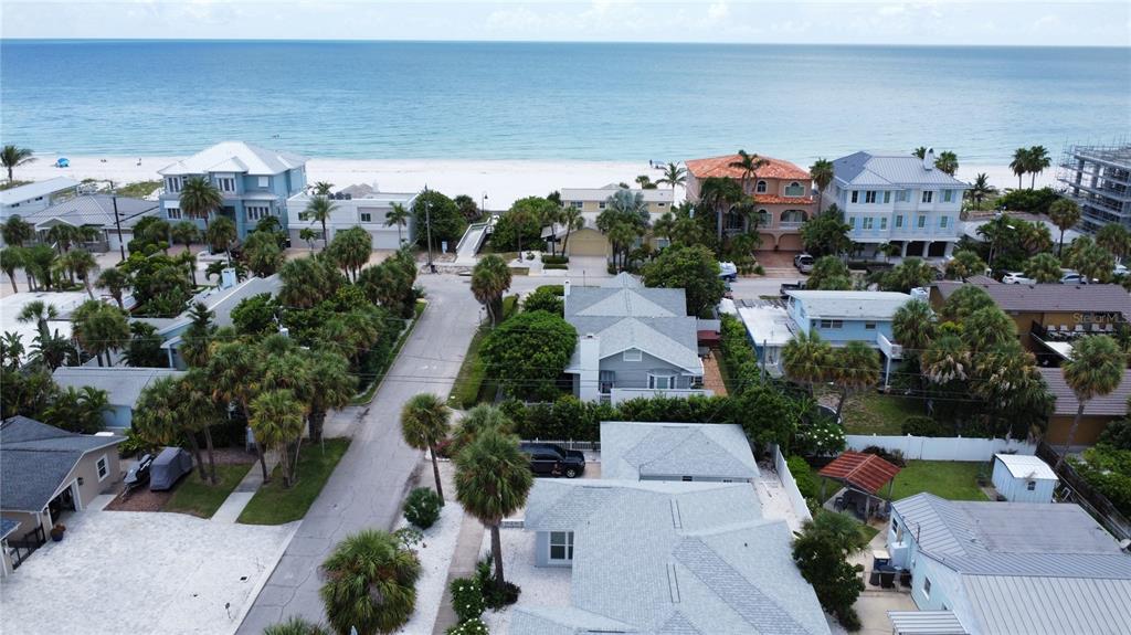 An aerial view shows a coastal neighborhood with houses, palm trees, and a sandy beach — 850 MANDALAY AVENUE, CLEARWATER BEACH, FL