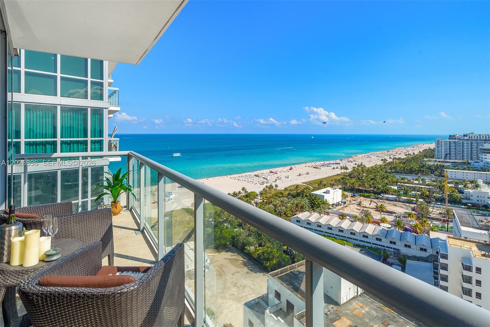 A balcony with outdoor seating overlooks a sandy beach and the ocean — 101 20th St # 2404, Miami Beach FL 33139, MIAMI BEACH, FL