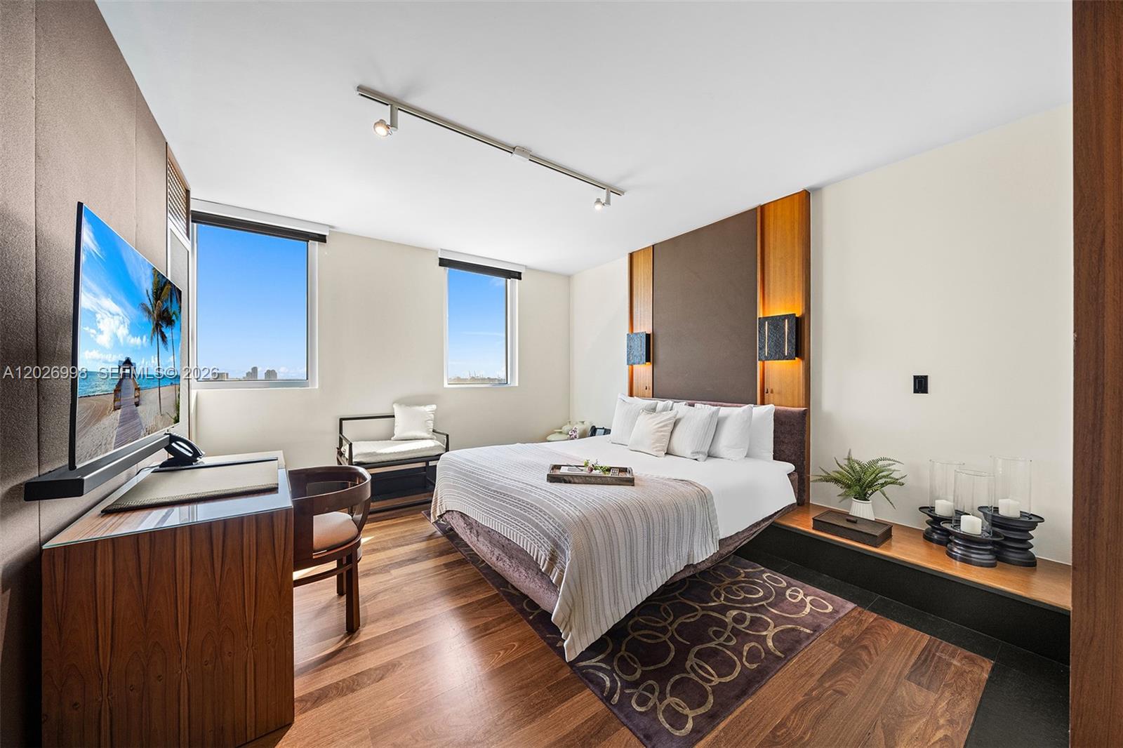 A modern bedroom features a king bed, wood flooring, a desk, and two windows — 101 20th St # 2404, Miami Beach FL 33139, MIAMI BEACH, FL
