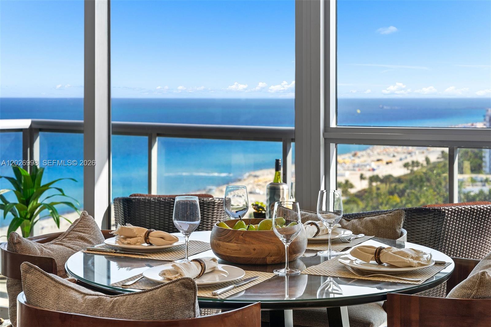 A dining area with a glass table overlooks the ocean through floor-to-ceiling windows — 101 20th St # 2404, Miami Beach FL 33139, MIAMI BEACH, FL